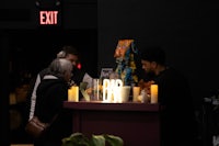 a group of people standing at a bar with candles