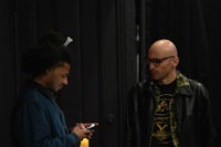 two men looking at a cell phone in a dark room