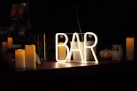 a bar with candles and a neon sign